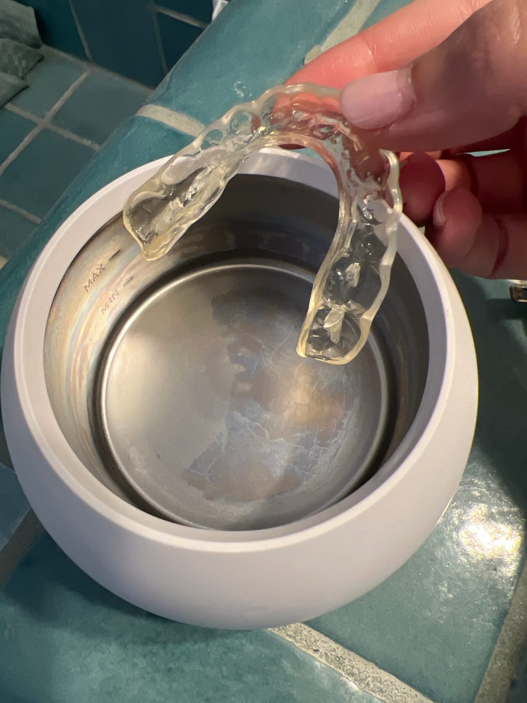 Hand lowering a clear retainer into the cleaner tank - customer photo from Marcus T.